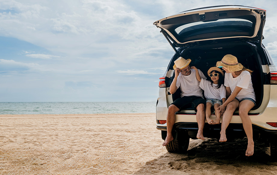 Family sitting in car trunk on the beach