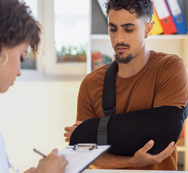 Young man in arm sling speaking with a doctor